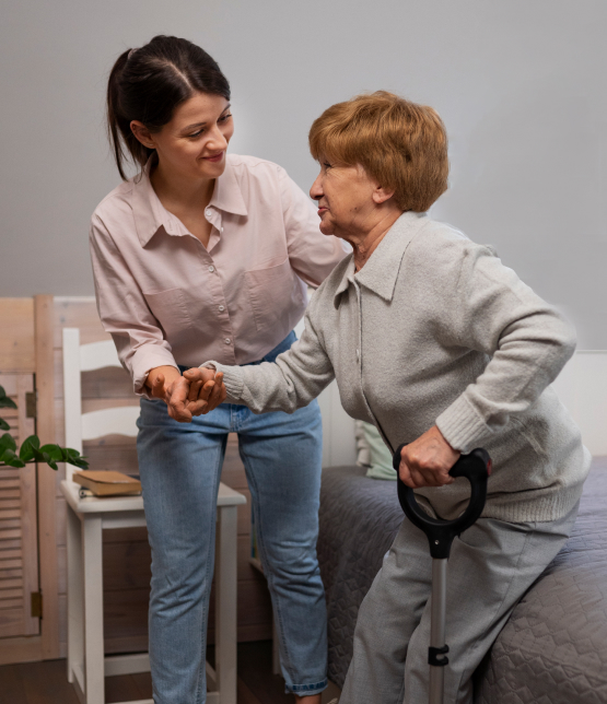 Female care worker assists elderly woman standing with walking stick, providing personal elderly care at home