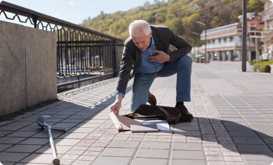 Elderly man fallen outdoors, clutching chest; walking stick nearby. Highlights need for emergency elderly care