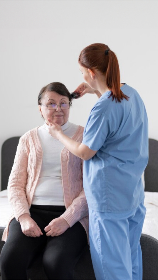 A female care worker grooms elderly woman's hair