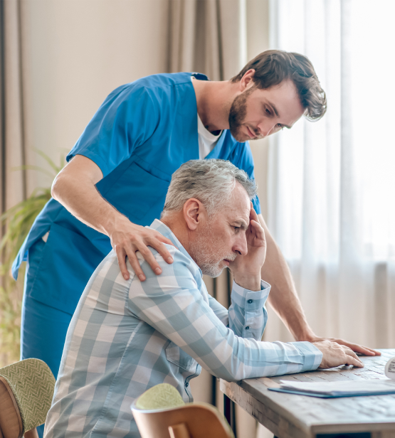 Care worker comforts distressed elderly man at home, illustrating supportive domiciliary care services