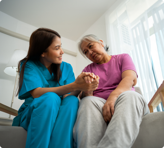 Female care worker holds hands with elderly woman, offering supportive dementia care and companionship